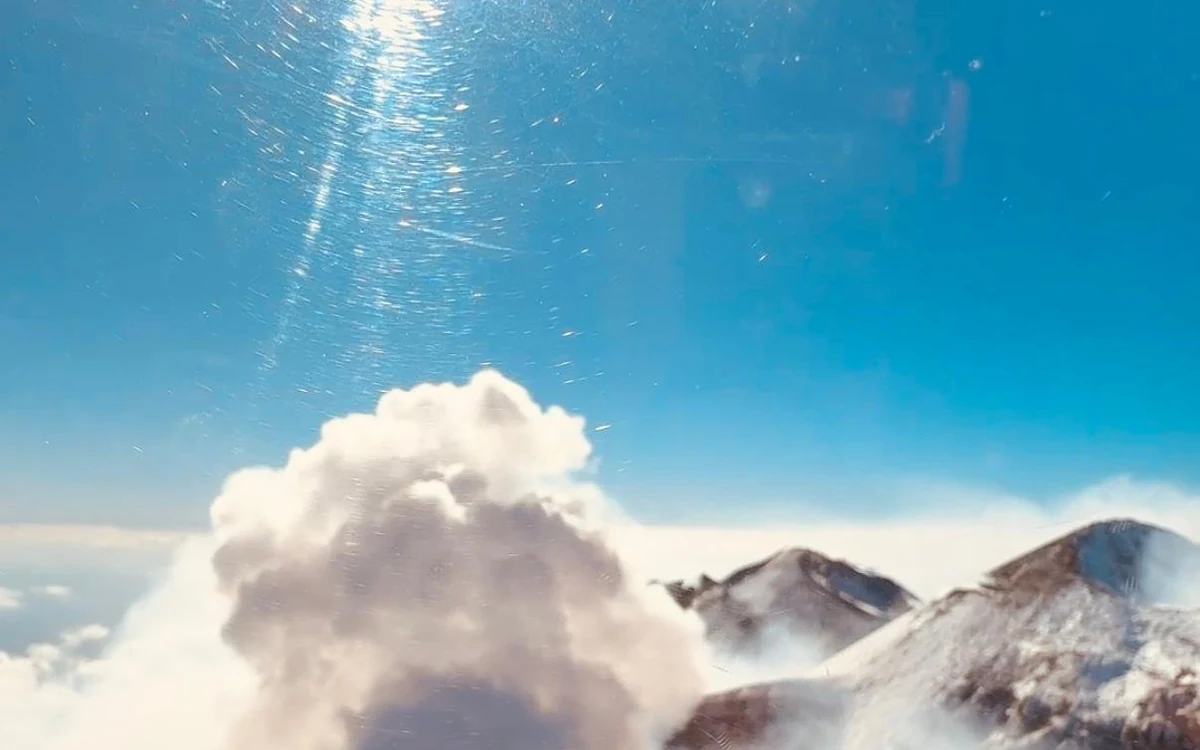 A layer of cloud sitting below the upper cone of Etna, seen from the air