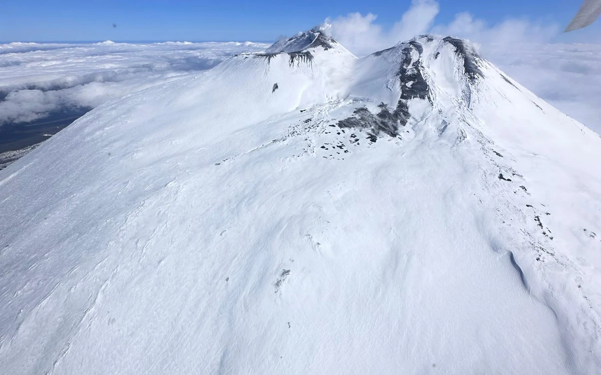 The summit craters of Etna photographed from a helicopter, with the dark cone and the lighter ground around it