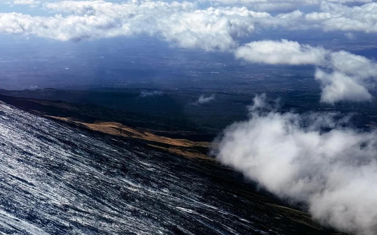 The coastal plain below Etna seen from a helicopter, with a line of cloud lying across the higher ground