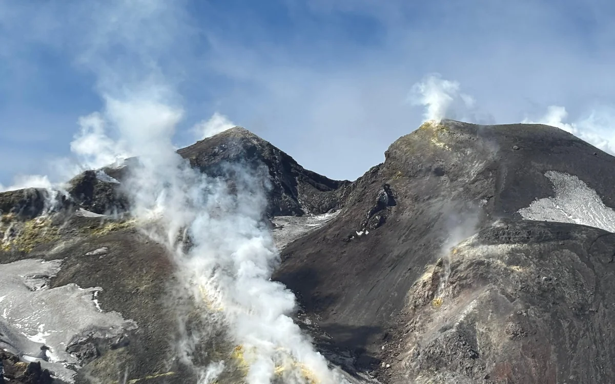 The summit craters seen from the air, with steam drifting from the rim